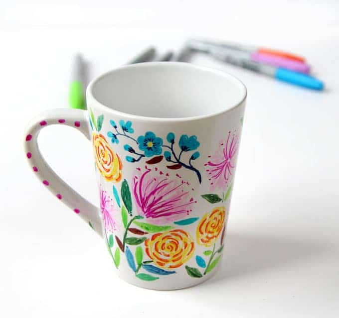 A white mug decorated with flowers using sharpie markers