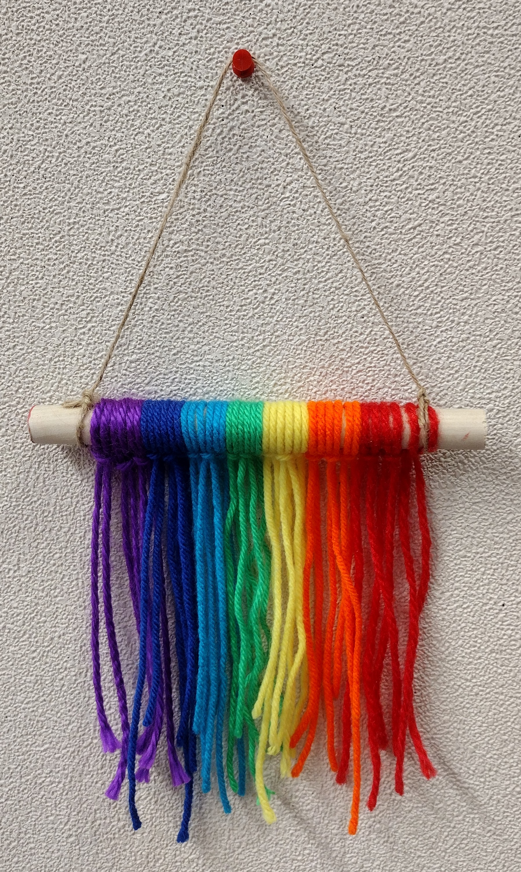 Rainbow yarn wall hanging decoration on a 6 inch wooden rod. 