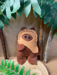 Brown felt Ewok character with sticks and leaves.